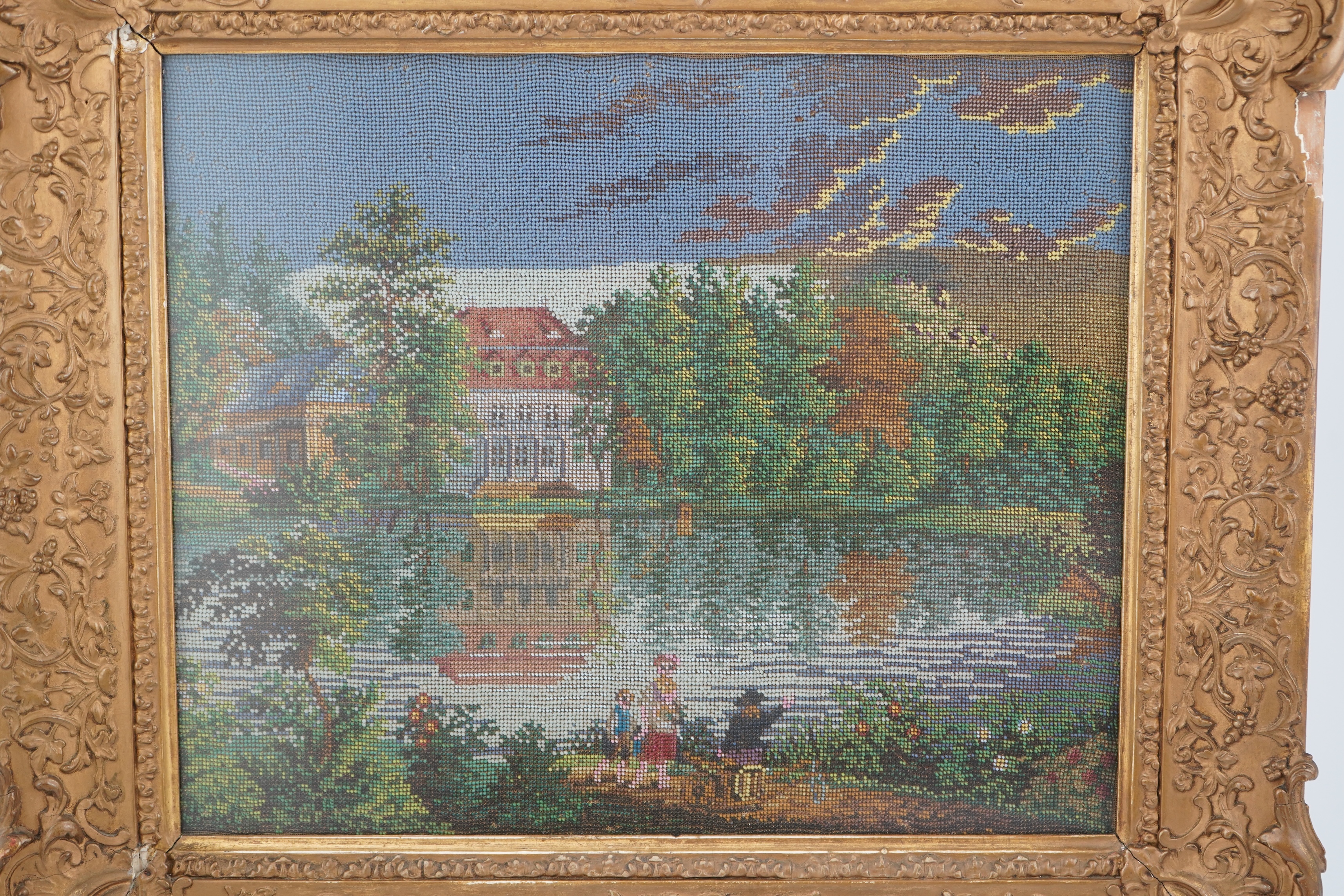 A 19th century framed Berlin beadwork panel, possibly German, country scene of a family walking along a garden path, away from a large lake and mansion surrounded by a forest of fire trees. 26cm wide x 30cm high. Conditi